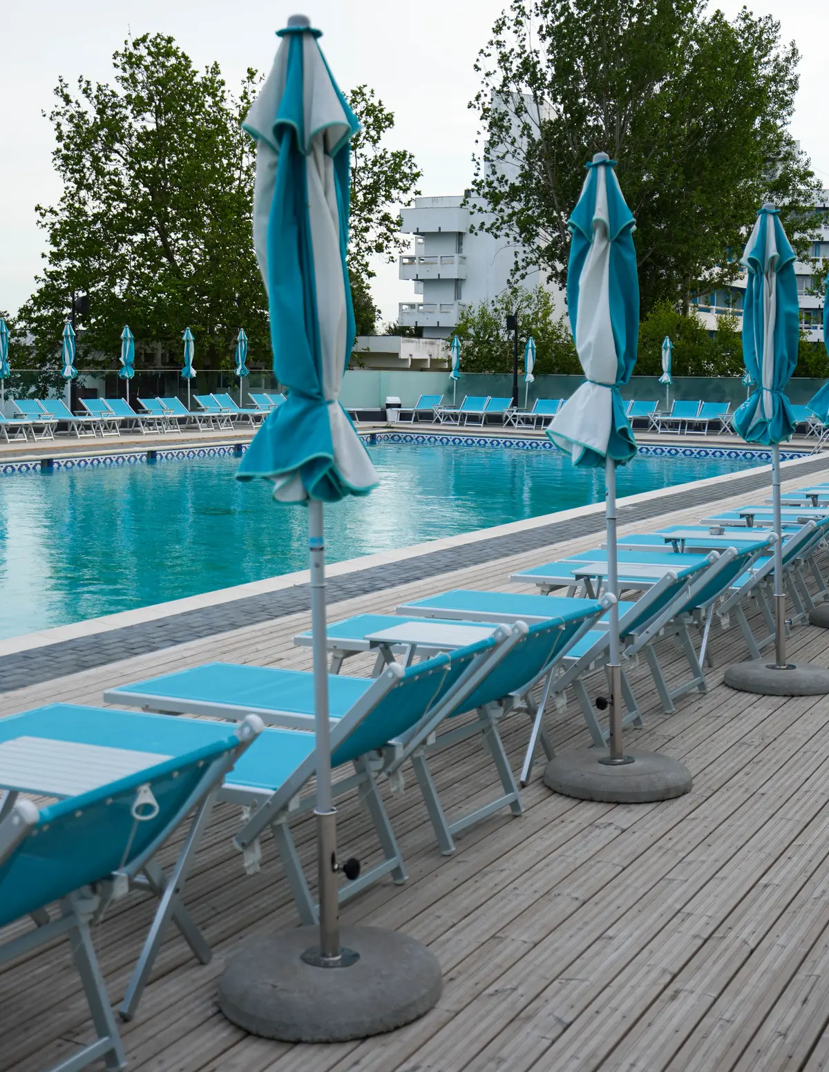 Umbrele și șezlonguri pe marginea piscinei