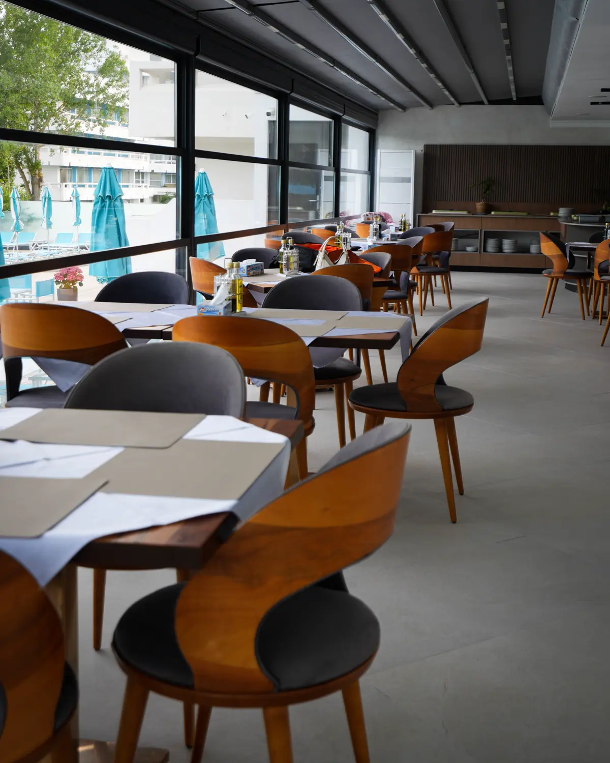 Sala restaurantului, cu ferestre mari spre piscină