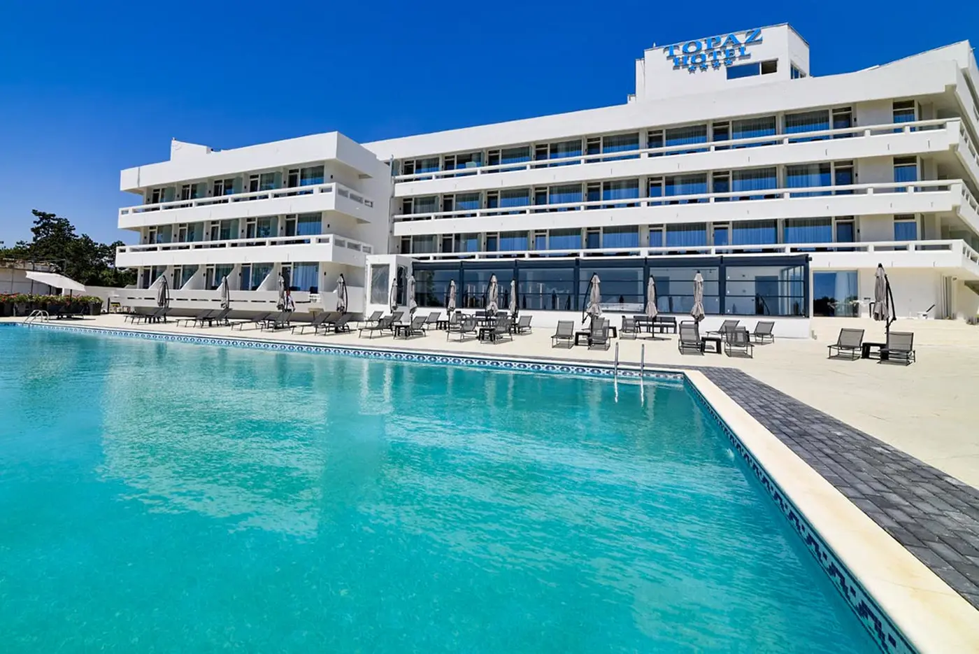 Fațada lungă a hotelului și piscina exterioară