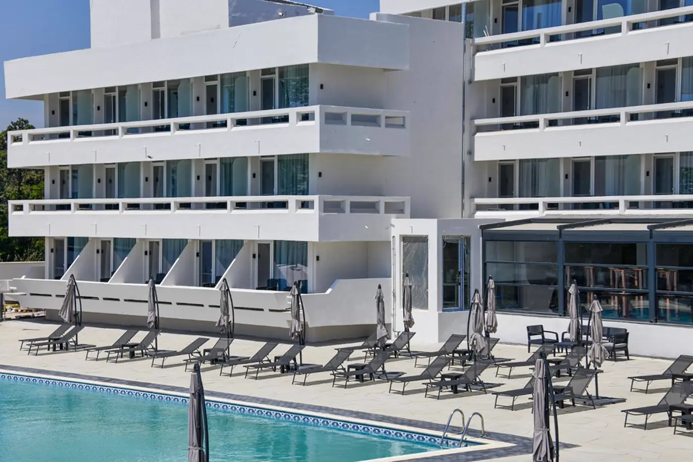 Clădirea hotelului și șezlongurile de lângă piscină